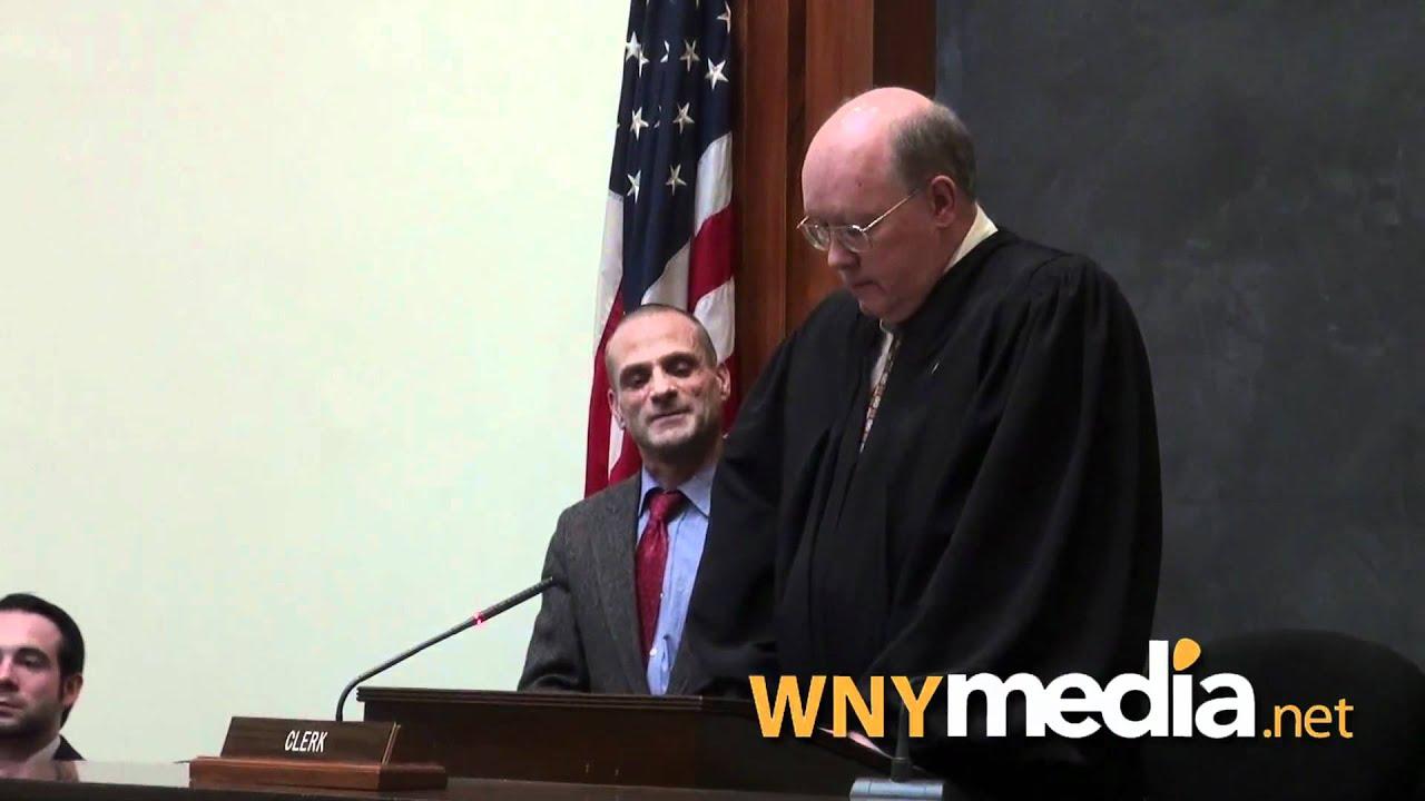 Officials in robes stand at a podium with a U.S. flag behind them