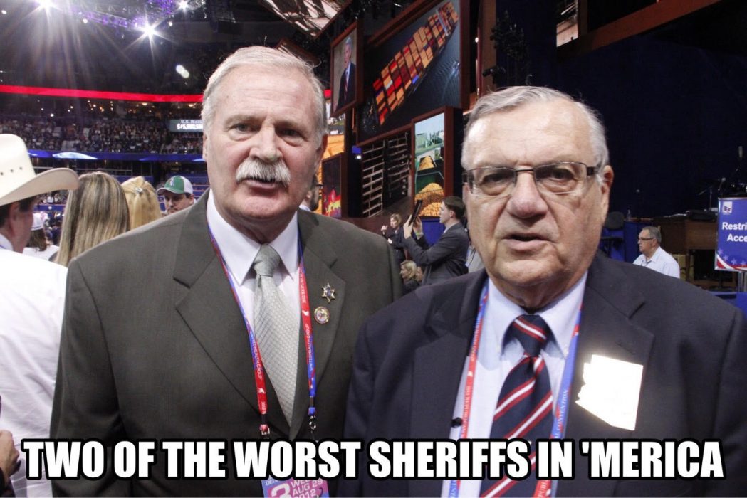 Two suited men stand together at a convention with text overlay reading “TWO OF THE WORST SHERIFFS IN 'MERICA”.