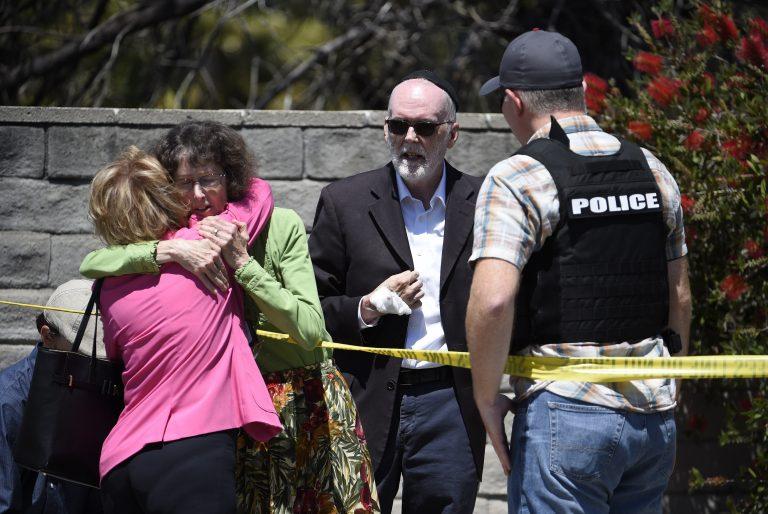 Uniformed police officer and security tape as a woman in a pink jacket covers her face.