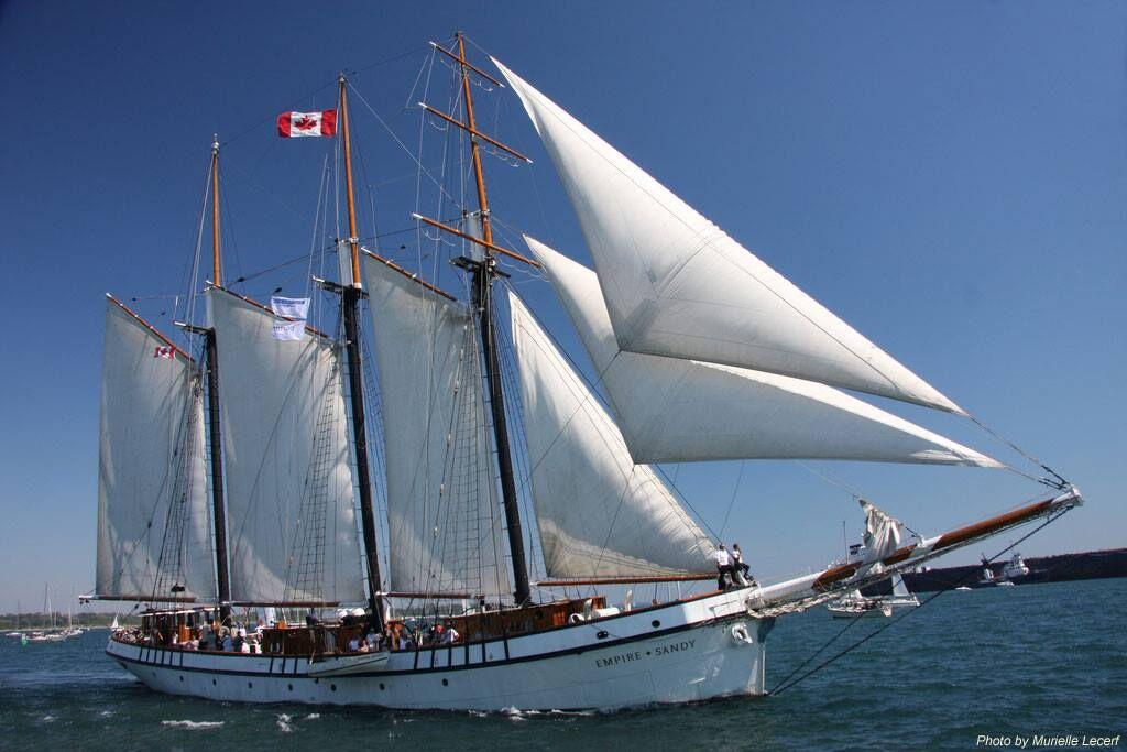 Tall sailing ship with large white sails moving across the water