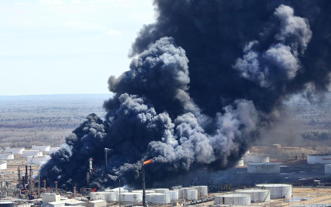 Factory smokestacks emit dense dark smoke over an industrial facility