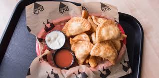 Tray of pierogi with small cups of sour cream and red dipping sauce