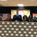 People stand behind stacked cardboard boxes labeled with thank-you notes.