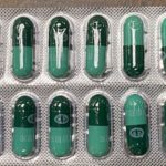 Green capsule pills in a clear blister pack arranged in rows.