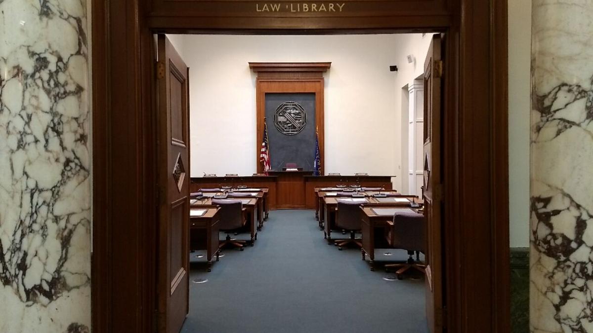 Courtroom interior with a central podium, seal backdrop, and rows of desks.