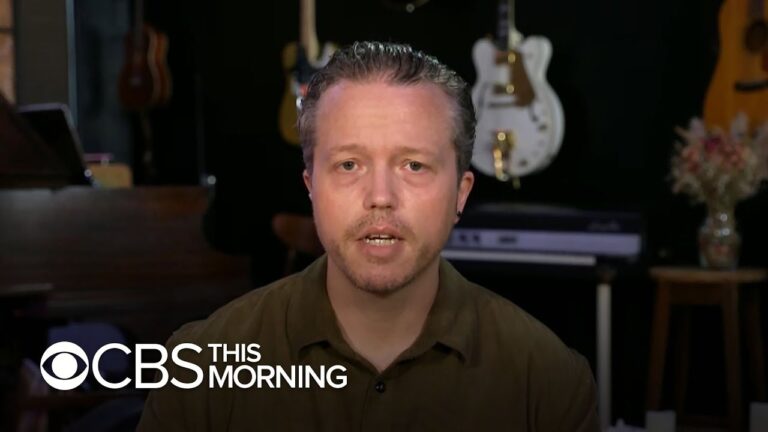 Man speaks on camera in a room with guitars and a piano, CBS This Morning watermark