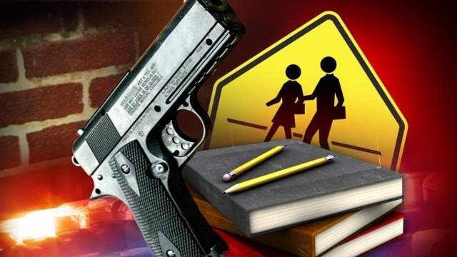 Handgun with bright muzzle flash beside books, pencils, and a school crossing sign.