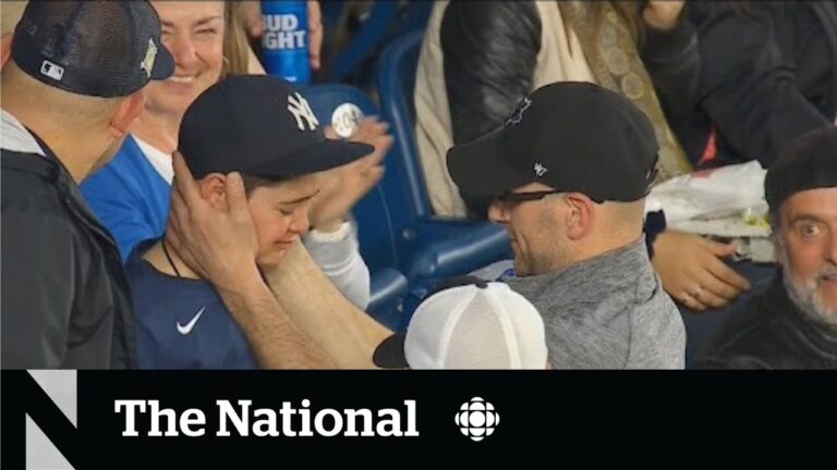 Fans in baseball caps embrace and smile in stadium seating; The National logo appears below.