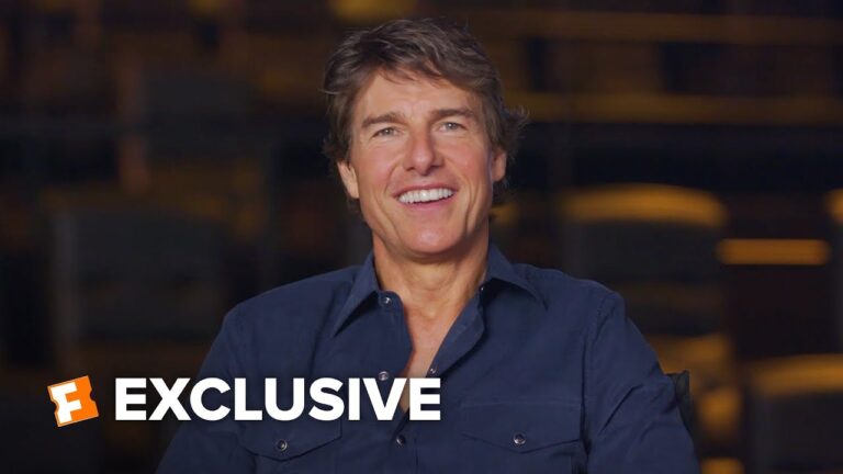 Smiling man in a dark shirt with an “EXCLUSIVE” banner overlay