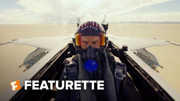 Pilot in a fighter jet cockpit, centered with jets wings visible behind, text reads "FEATURETTE".