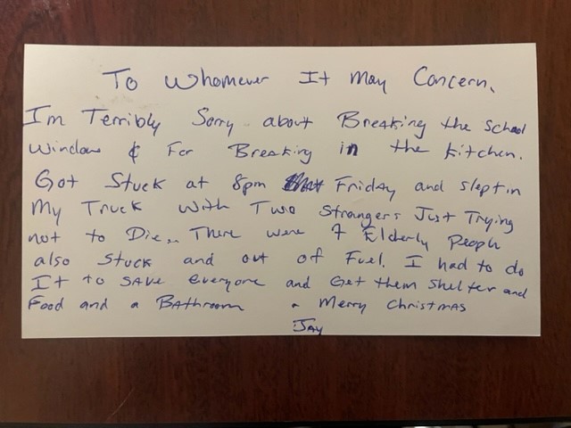 Handwritten letter on white paper with blue ink, pinned to a wooden board.