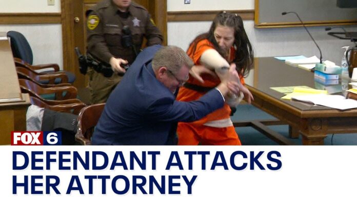 Person in suit embraces another in orange jail uniform in a courtroom setting.