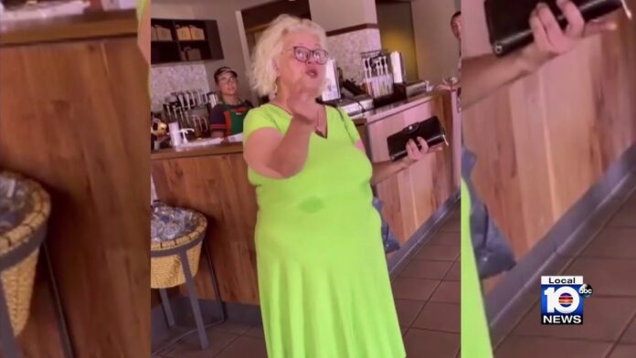 Woman in a bright green dress speaks near a service counter in a café