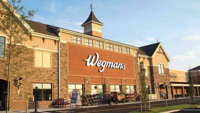 Wegmans logo on a brick storefront with parking area and landscaping