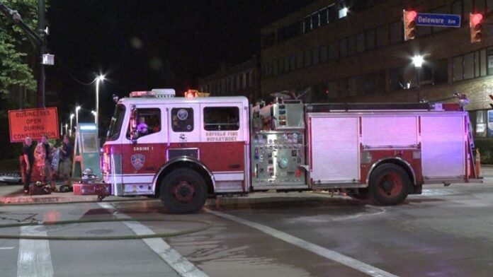 Two fire engines parked at night on a city street under streetlights.