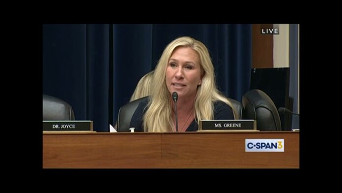 Blonde woman speaks at a hearing podium with nameplates and C-SPAN logo