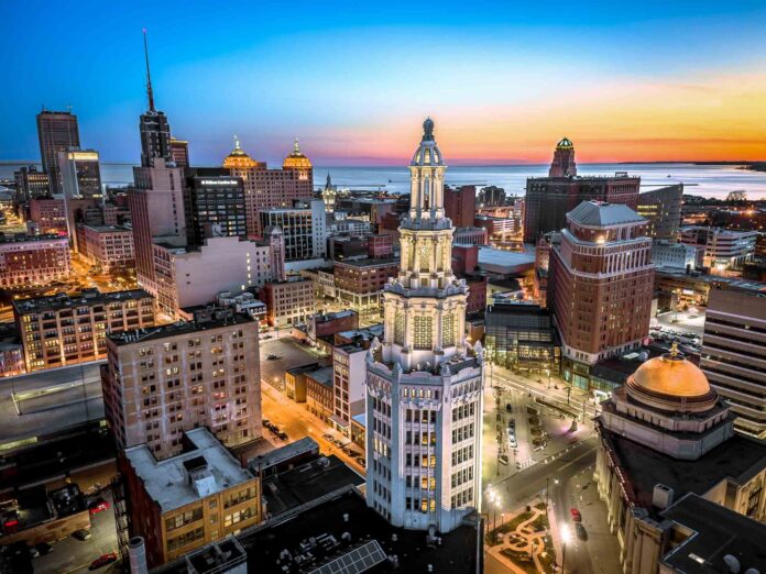 Aerial view of downtown buildings and a domed courthouse at sunset over Lake Erie.