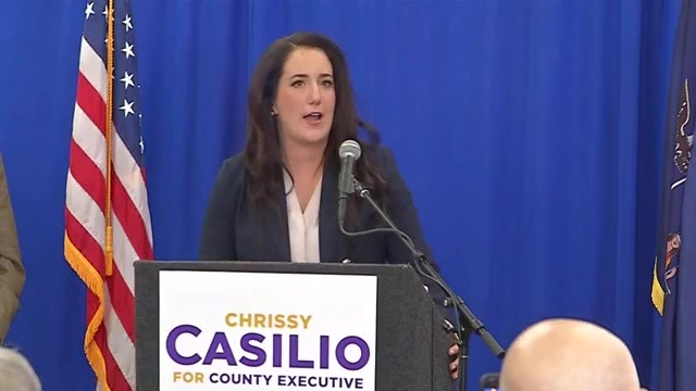 Woman speaks at a podium with a sign reading Chrissy Casilio for County Executive.