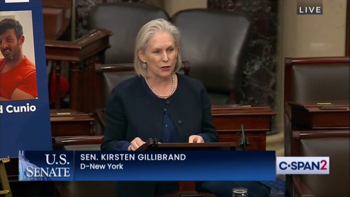 Senator in a dark blazer speaks at a desk in a U.S. Senate chamber