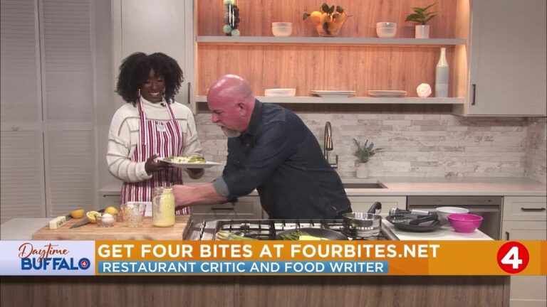 Host in striped apron serves food to a man cooking at a stove in a TV kitchen set