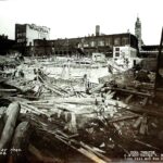 Demolition site with rubble and beams in front of a Wurlitzer sign and Shea Theatre facade.