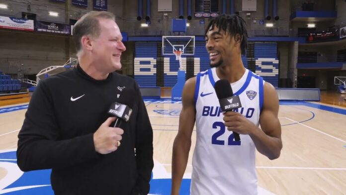 Interview in a basketball arena as a man in a Buffalo uniform smiles.