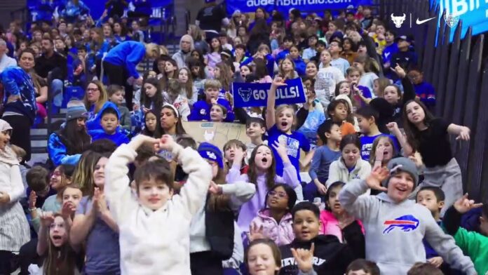 Large group of children cheering and celebrating in a sports arena stands