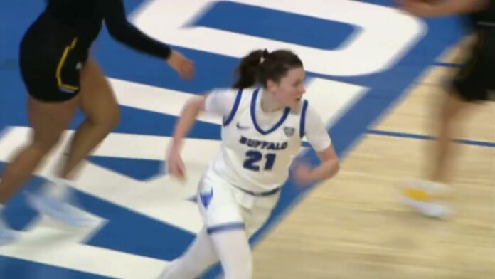 Female basketball player in white and blue jersey dribbling on a court with blue-and-white markings.