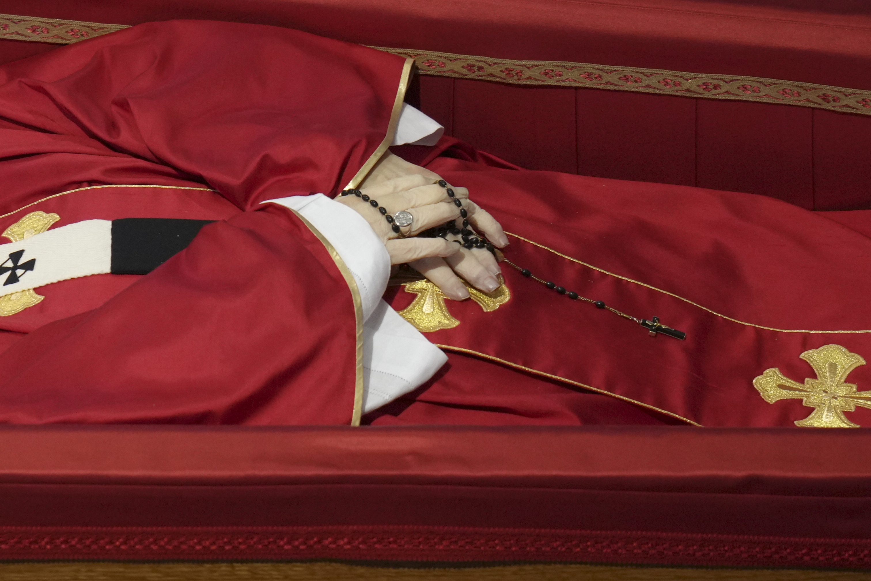 Pope Francis' hands clasping a rosary as his body lies in state