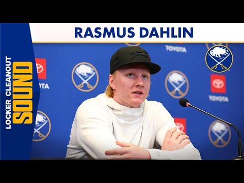 Rasmus Dahlin seated at a press conference with microphones and a team backdrop.