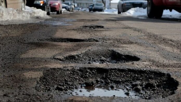 Close view of an asphalt street repair area with dark patch and small puddle