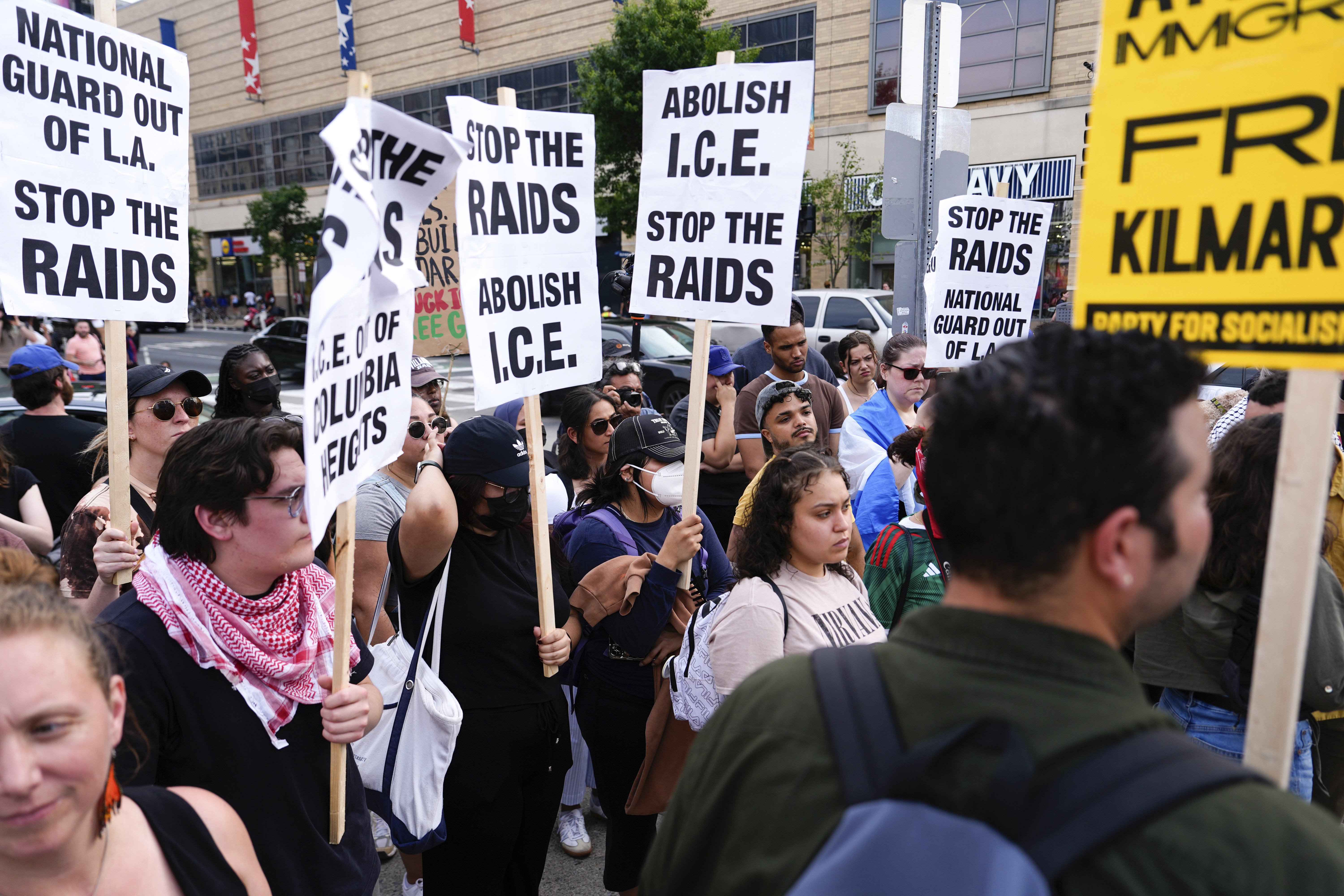 Demonstrators hold signs during protest against ICE raids