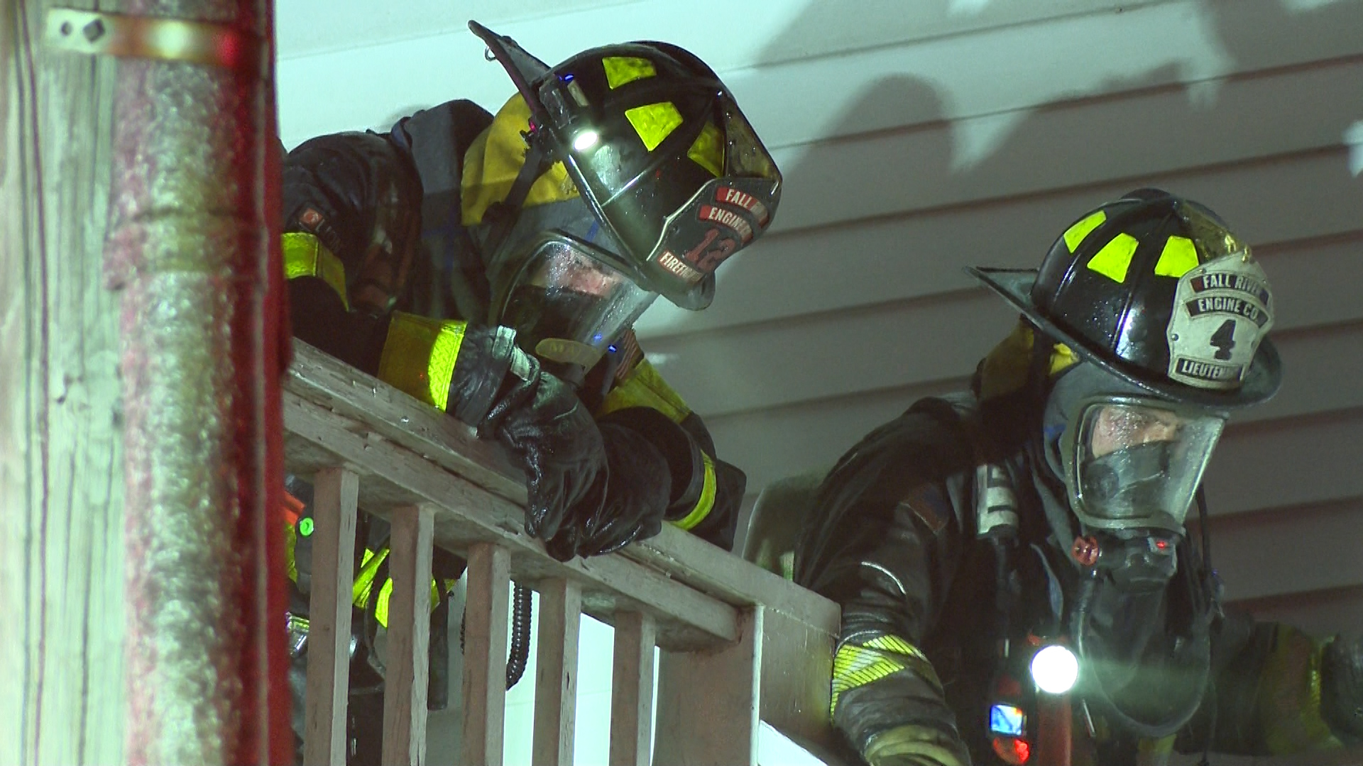 A firefighter in full gear leans over a railing